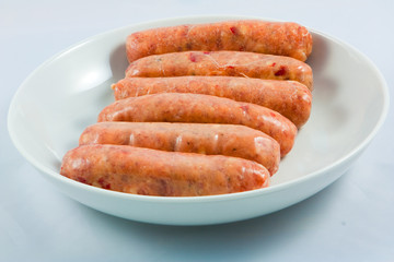 A white bowl of raw sweet chilli sausages