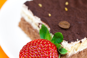 cake on a plate and strawberries lying on the orange fabric