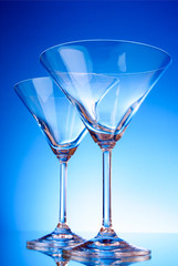 Two empty glasses of martini on the light blue background