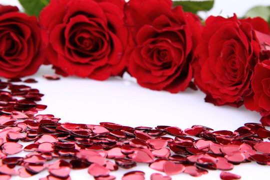 Red rose and heart shaped confetti on white background