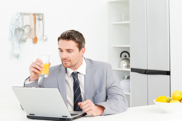 Businessman drinking while he is looking at his laptop