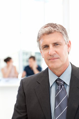 Fototapeta premium Businessman looking at the camera while his team is working