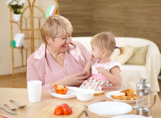 grandmother feeding granddaughter at home