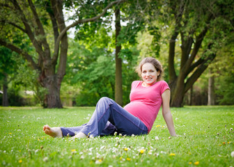 Naklejka na ściany i meble Beautiful pregnant woman in the park