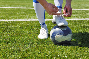 Human leg and soccer ball on the grass field