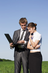 Two successful workers in the street with a laptop