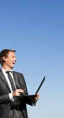 Positive successful businessman with a laptop on a sunny spring