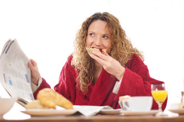 Junge Frau am Frühstückstisch mit Tageszeitung