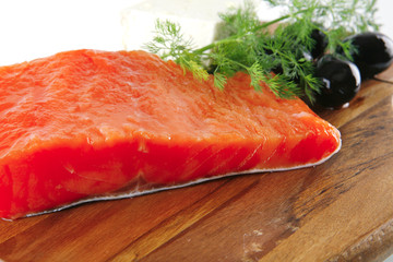 pink smoked salmon on wooden plate with white cheese