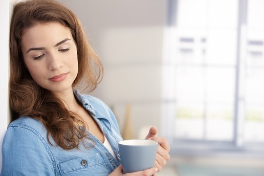Pretty female daydreaming drinking tea