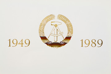 Staatswappen der DDR (goldene Lettern im Hochdruck auf Papier)
