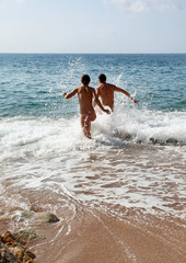 Young couple running through water in the sea