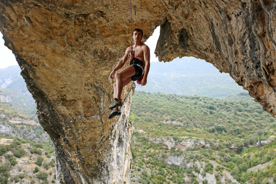 Rock climber hanging on the rope after reaching the top