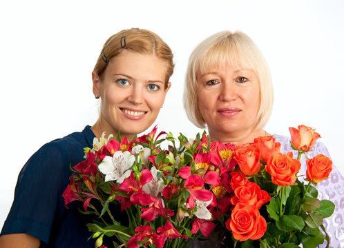 Two smiling women with flowers on white background