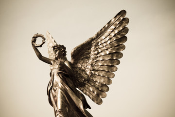 Silver angel statue with olive crown in hand.
