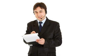Smiling businessman with headset making notes in document