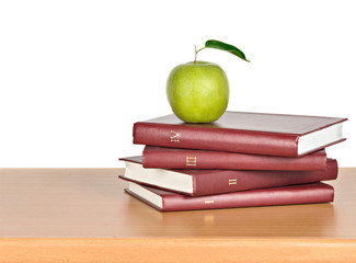 Green apple on pile of books on white background