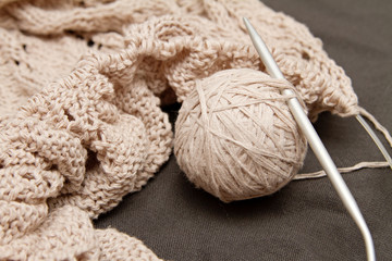 Fototapeta na wymiar a beige knitted shawl with round needles