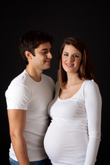 Fototapeta premium Loving dad and mom with pregnant belly isolated on black