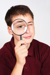 Fototapeta na wymiar young man holding magnifier and looking through it, big eye