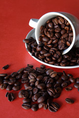 chicchi di caffè con tazza su fondo rosso