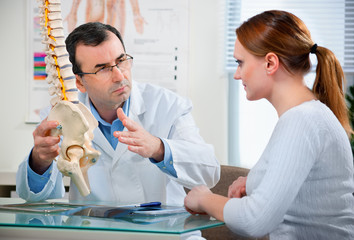 Doctor shows the problem areas on the spine's model to patient
