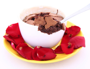 Chocolate souffle with red rose petals being eaten with a spoon