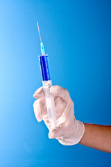 Syringe in doctors hand over blue background