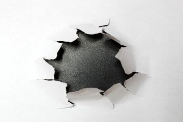 Loch in Papier vor schwarzem Hintergrund