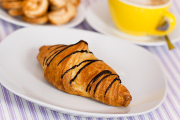 Cappuccino mit Croissant mit Schoko-Überzug