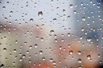 Drops of rain on a window pane, buildings in background