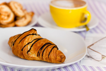 Cappuccino mit Croissant mit Schoko-Überzug