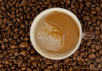 Cup of coffee with coffee beans on background