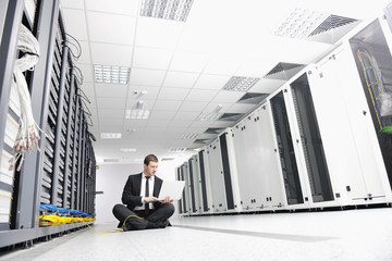 businessman with laptop in network server room