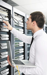 businessman with laptop in network server room