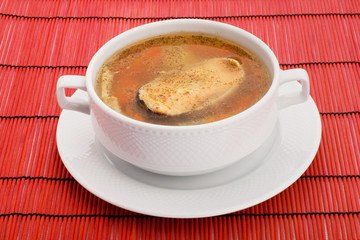 Soup with salmon and hot peppers on a red background