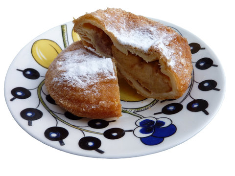 A cut up fritter of apple with powdered sugar on a plate