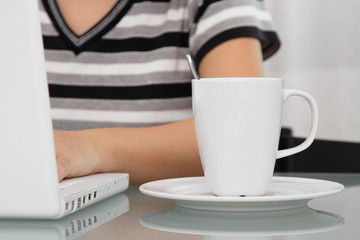 A coffee mug in front of a working woman