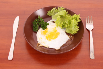 Frying egg with fork and knife on the table