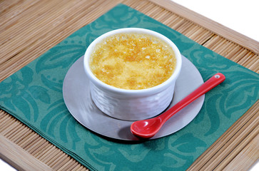 Little home-made custard with a red spoon on a bamboo tray