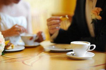 Coffee cup on a table (bride and groom on a background)