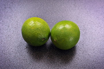 Two whole limes on a kitchen table