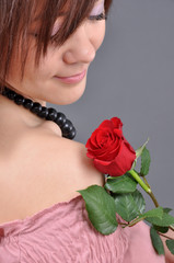 A girl holding a red rose in her hand.