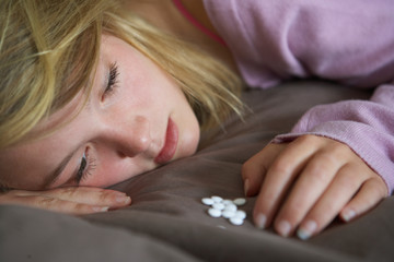Obraz na płótnie Canvas Depressed Teenage Girl Sitting In Bedroom With Pills