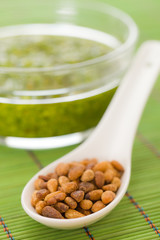 Pine nuts in a spoon with pesto
