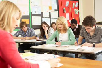 Teenage Students Studying In Classroom With Teacher