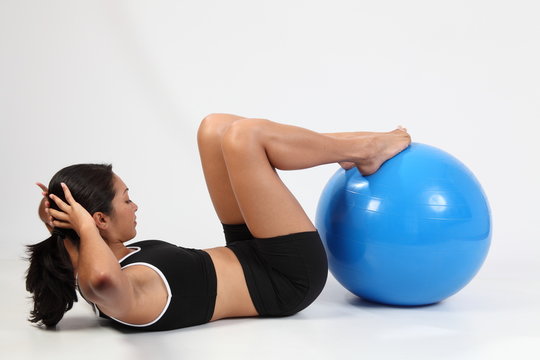 Athletic young sports woman doing crunches on exercise ball