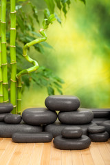 Fototapeta na wymiar Black spa stones on green bamboo background