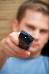 Young guy looking at camera while switching TV channels