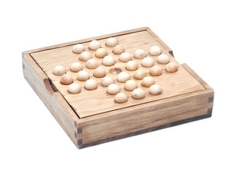 Wooden soiltaire board with pieces shot over white